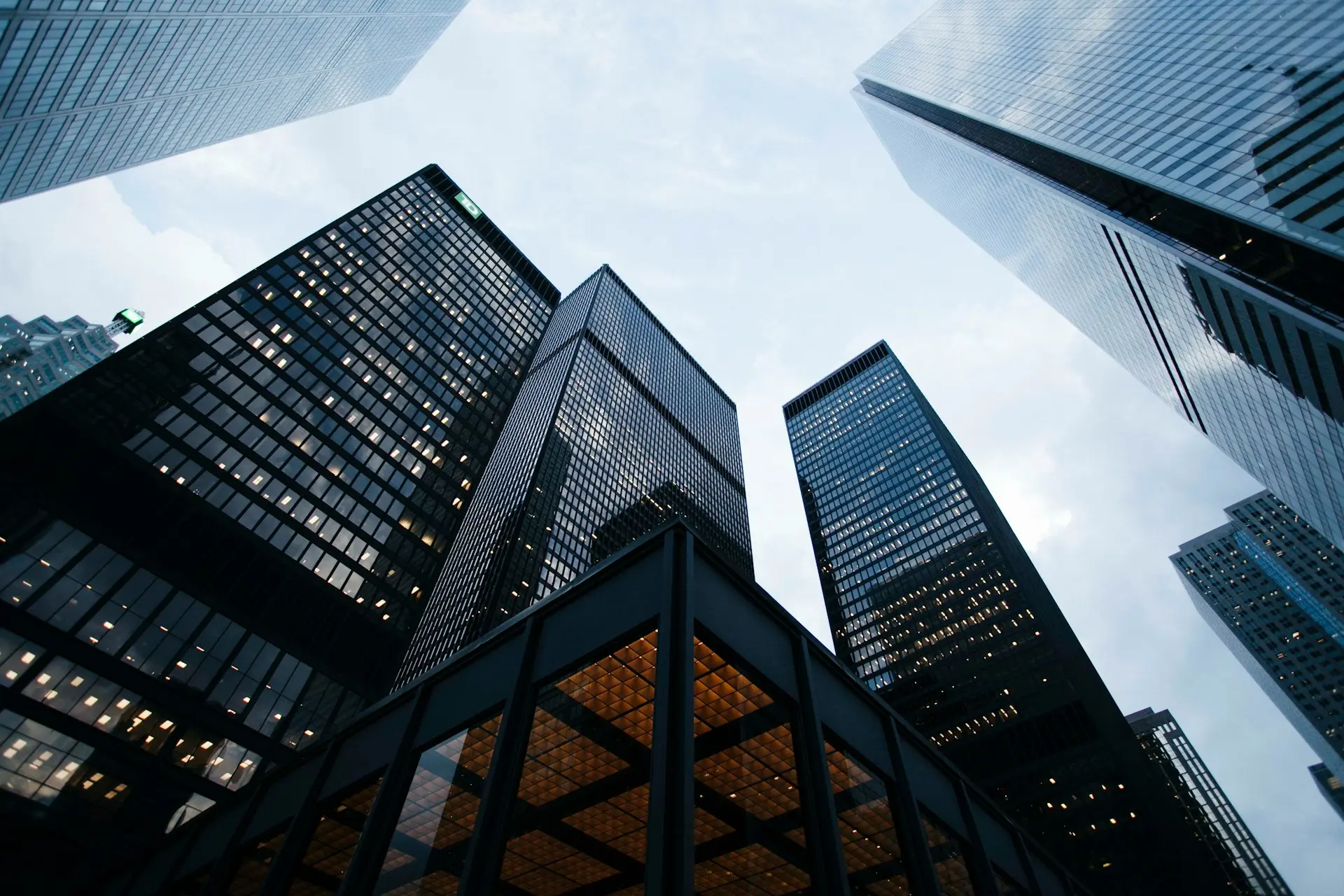 Fotografía en ángulo contrapicado que muestra grandes rascacielos de cristal y estructuras corporativas modernas alzándose hacia el cielo.